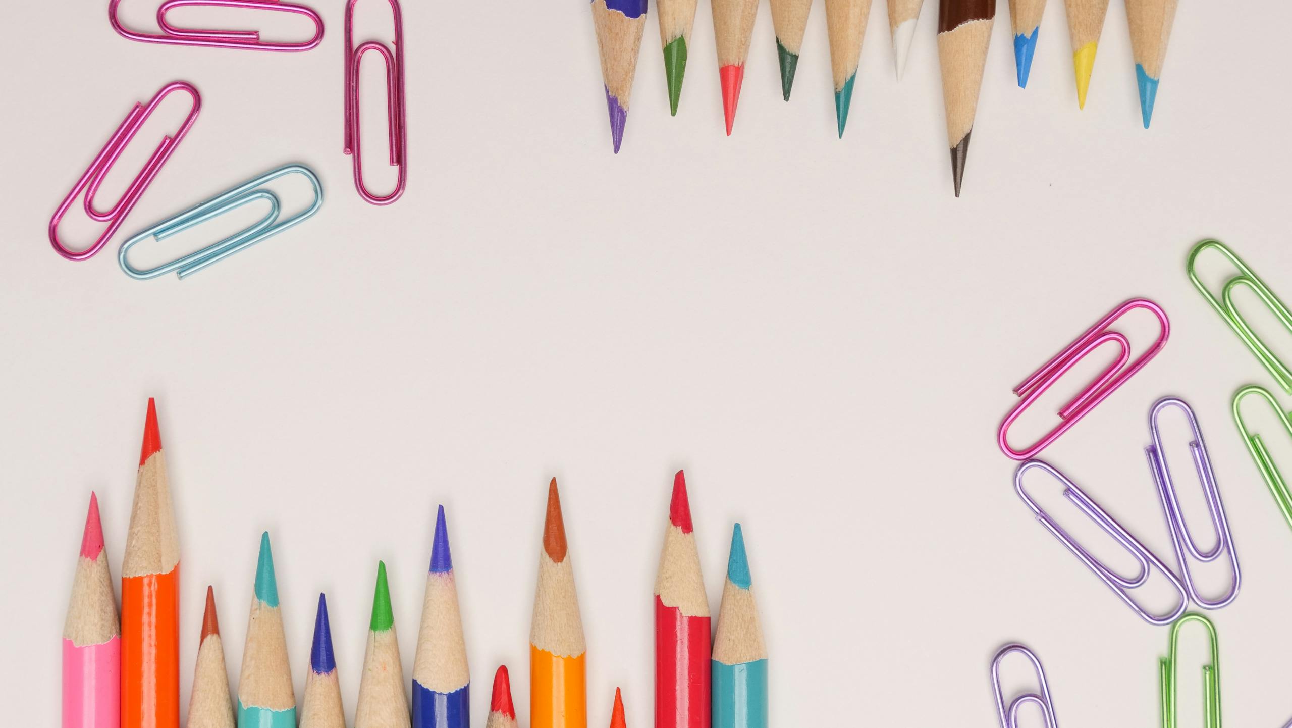 Vibrant colored pencils and paper clips on a light background provide a playful stationery design.